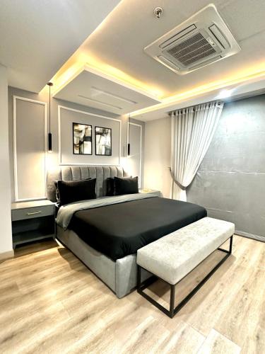 拉合尔Gold crest mall Two Bed Luxury Apartment - Mirhaa Homes的一间卧室配有一张黑色大床和长凳