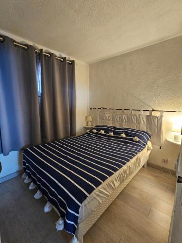a bedroom with a large bed with blue and white stripes at Portvendres Sea view in Port-Vendres