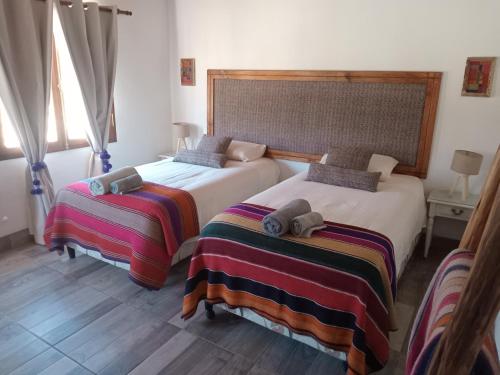 two beds sitting next to each other in a bedroom at Cabañas La Nochera in Tilcara
