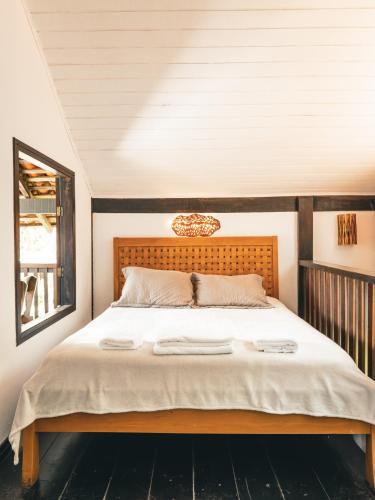 a bedroom with a large bed with a wooden headboard at Casa Pindorama - Chalé Opy in Paraty