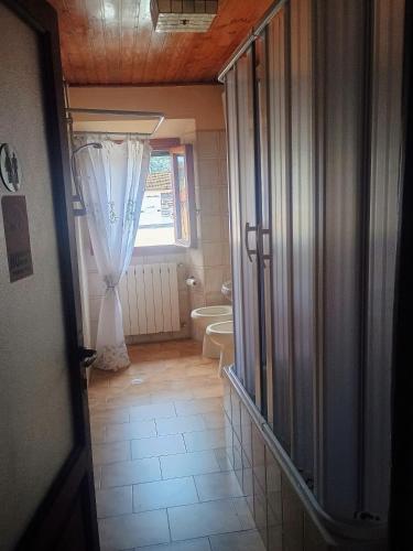a bathroom with a toilet and a window with a curtain at La Divina guest house in Pontassieve