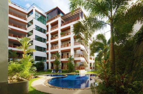 an apartment building with a swimming pool and palm trees at 41 квадратный метр, апартамент на пляже Сурин in Surin Beach
