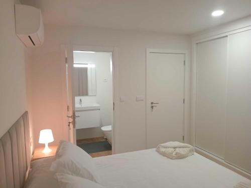 a white bedroom with a bed and a bathroom at Apartamento Sonho Jardim in Ponta Delgada