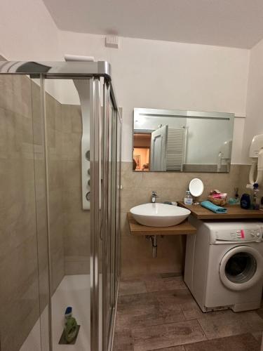 a bathroom with a sink and a shower and a washing machine at SalitaCentrale6 in Bellagio