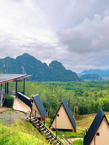 Un grupo de pequeñas casas con montañas al fondo. en Khaosok Campsite, en Khao Sok