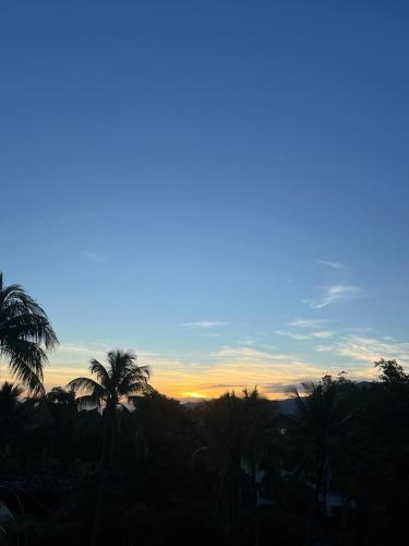 a sunset with palm trees in the foreground at Ótima casa próxima a praia e o centro in Ilhabela