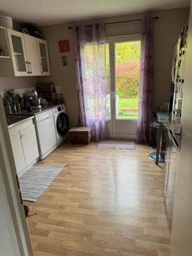a kitchen with a wooden floor and a large window at Chez Dapia in Saint-Denis-en-Val