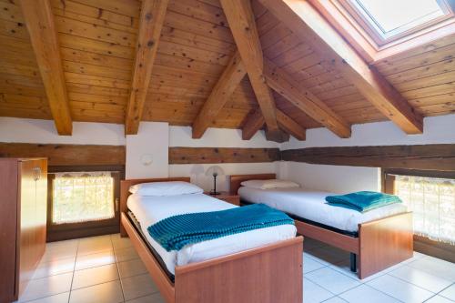 two beds in a room with wooden ceilings and windows at Stars Apartments Gressan in Cerise