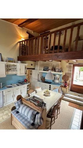 Una sala de estar con una mesa y una cocina. en Maison Le puits du bonheur, en La Celle-sous-Gouzon