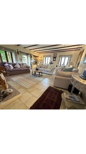 Una gran sala de estar con sofás y una mesa. en Maison Le puits du bonheur, en La Celle-sous-Gouzon