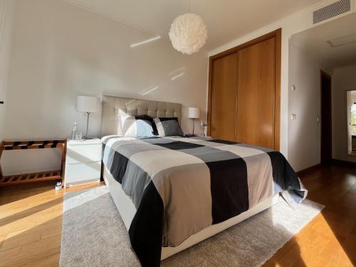 a bedroom with a large bed with a black and white comforter at Parque Nações - premium location and river view in Lisbon