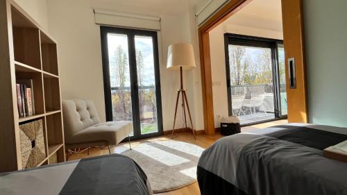 a bedroom with a bed and a chair and windows at Parque Nações - premium location and river view in Lisbon