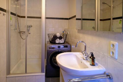 a bathroom with a sink and a shower and a washing machine at Zum Friedl in Wackersberg