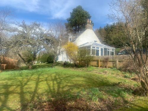 a large white house with a fence in a yard at Charming cottage close to the Cairngorms in Ballindalloch