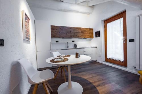 eine weiße Küche mit einem Tisch und Stühlen im Zimmer in der Unterkunft Petit Câlin - Le Four des Alpes in Rhemes-Saint-Georges