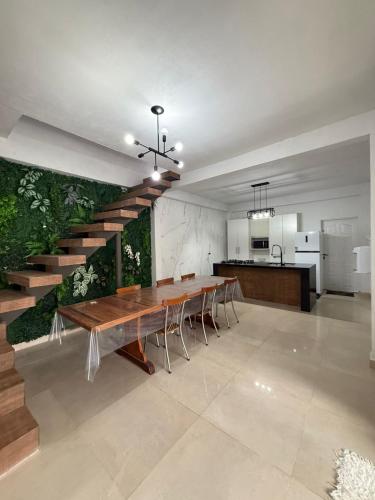 a dining room with a wooden table and a staircase at Casa Quintal de Bertioga Centro in Bertioga