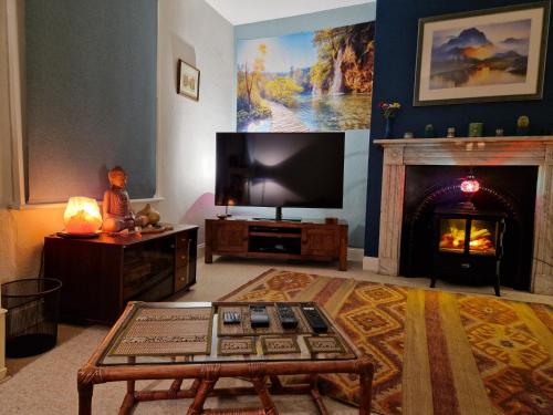 een woonkamer met een tv en een open haard bij West Street Views - Flat 1 in Wimborne Minster