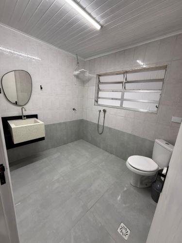 ein Badezimmer mit Toilette, Waschbecken und Spiegel in der Unterkunft Casa Quintal de Bertioga Centro in Bertioga