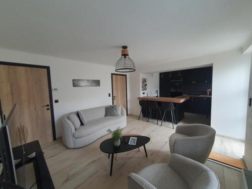 een woonkamer met een bank, stoelen en een tafel bij Le Mas d 'Ecaussinnes in Écaussinnes-dʼEnghien