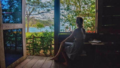 a woman sitting on a bench looking out a window at Casa Alma in Capurganá