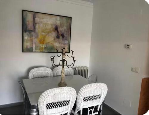 a dining room table with white chairs and a painting at coparelia 2 in Villarrobledo