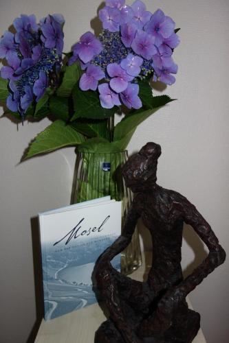 Eine Statue eines Mannes neben einer Vase lila Blumen. in der Unterkunft Ferienwohnung Belle Vue in Bernkastel-Kues