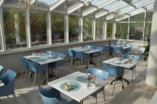 een restaurant met tafels, stoelen en ramen bij Pension Freudenthal in Wandersleben