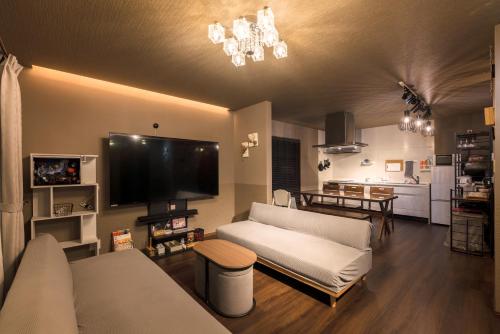 a living room with a couch and a flat screen tv at Noctis豊田 ジャグジー肩湯付お風呂75型TV 最大12名宿泊可能 in Toyota