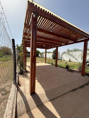 a wooden pergola with a fence in a field at Loft moderno con cocina americana y vistas a la montaña in Belén