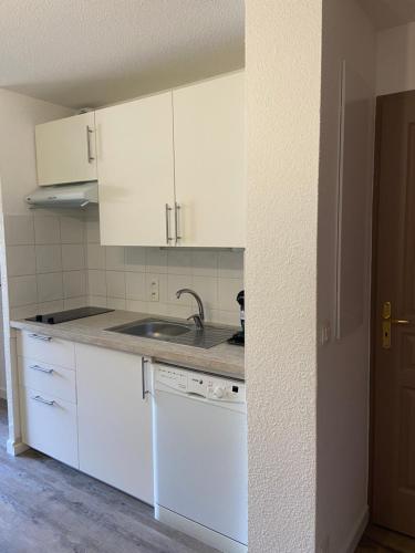 a kitchen with white cabinets and a sink at Chalets des Evettes- appartement vue montagne in Flumet