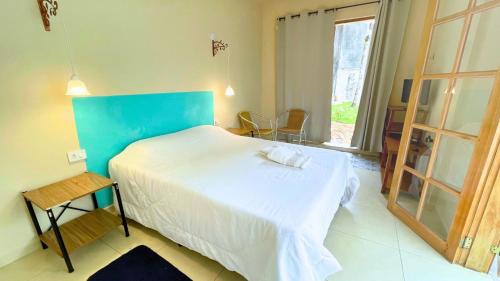 a bedroom with a large bed with a blue headboard at Suíte no Jardim in Peruíbe