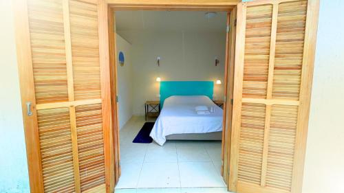 a small bedroom with a bed in a room with wooden doors at Suíte no Jardim à Beira-Mar in Peruíbe