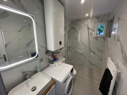 a white bathroom with a sink and a mirror at Pavillion Peuple de l'Herbe in Carrières-sous-Poissy