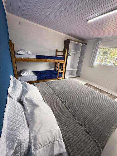 ein Schlafzimmer mit einem Bett und zwei Etagenbetten in der Unterkunft Casa Quintal de Bertioga Centro in Bertioga