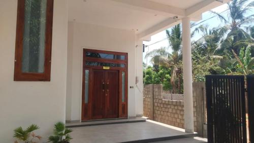 a wooden door on a house with a fence at Moon Guest House in Trincomalee