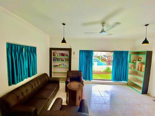 - un salon avec un canapé et des rideaux bleus dans l'établissement Sana Villa & Resort Goa, à Anjuna