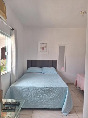 a bedroom with a large bed with a blue bedspread at 3 Kitnets in Rio das Ostras