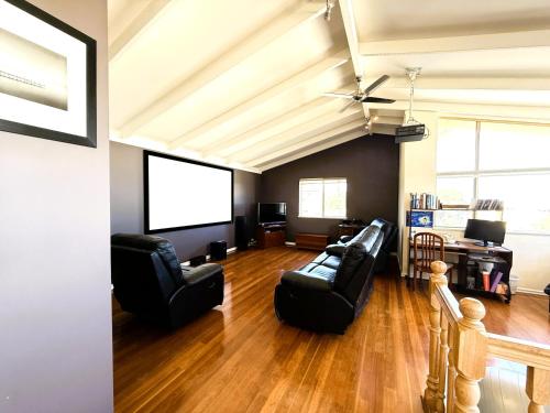 a living room with black leather furniture and a flat screen tv at 24 Sorrento Seabreeze 5br Family Seaside Home in Perth