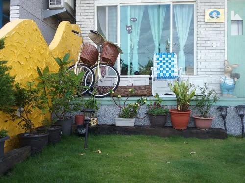 Ein Fahrrad, das an der Seite eines Hauses mit Pflanzen geparkt ist. in der Unterkunft Slowly B&B in Taitung