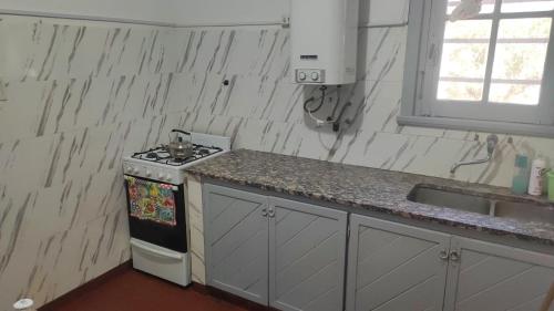 a kitchen with a stove and a sink at Alquilo Casa Miramar in Miramar