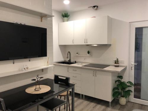 a kitchen with white cabinets and a table and a television at Casa das Oliveiras