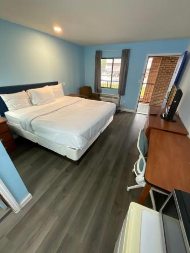 a bedroom with a large white bed and a desk at Oak Tree Inn in Irvine