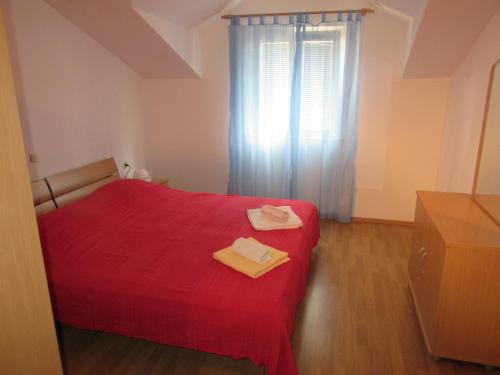 a bedroom with a red bed with a red blanket at Apartments Jerica in Bol