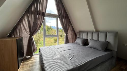 a bedroom with a bed and a large window at Cozy cottage with mountain view in K'obulet'i