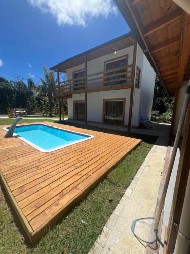 a house with a wooden deck and a swimming pool at Suíte no Rancho Minas in Porto Seguro