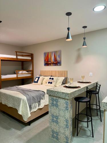 a bedroom with a bed and a bar with chairs at Suítes da Grazi - Centro Arraial do Cabo in Arraial do Cabo