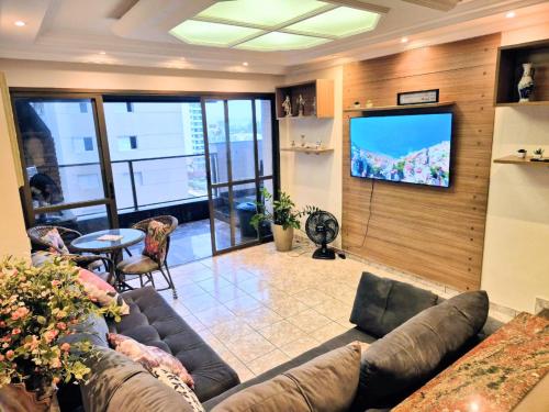 a living room with a couch and a flat screen tv at Varandas do Atlântico in Guarujá