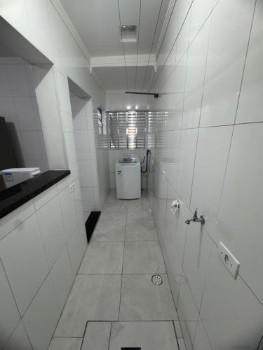 La salle de bains blanche est pourvue d'un lavabo et d'un lave-linge. dans l'établissement Yes João & Maria Casa inteira com garagem 7km aeroporto GRU, à Guarulhos