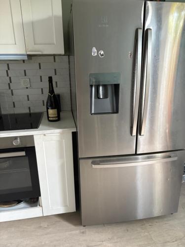 einen Kühlschrank aus Edelstahl in einer Küche mit einer Flasche Wein in der Unterkunft Chambre cozy avec lit double en étage in Bois-Colombes