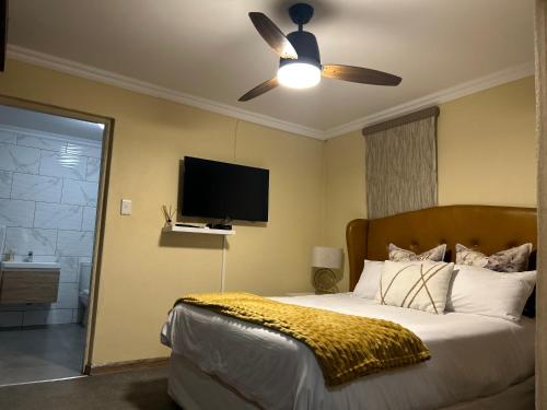 a bedroom with a bed with a ceiling fan and a television at Katlego in Bloemfontein